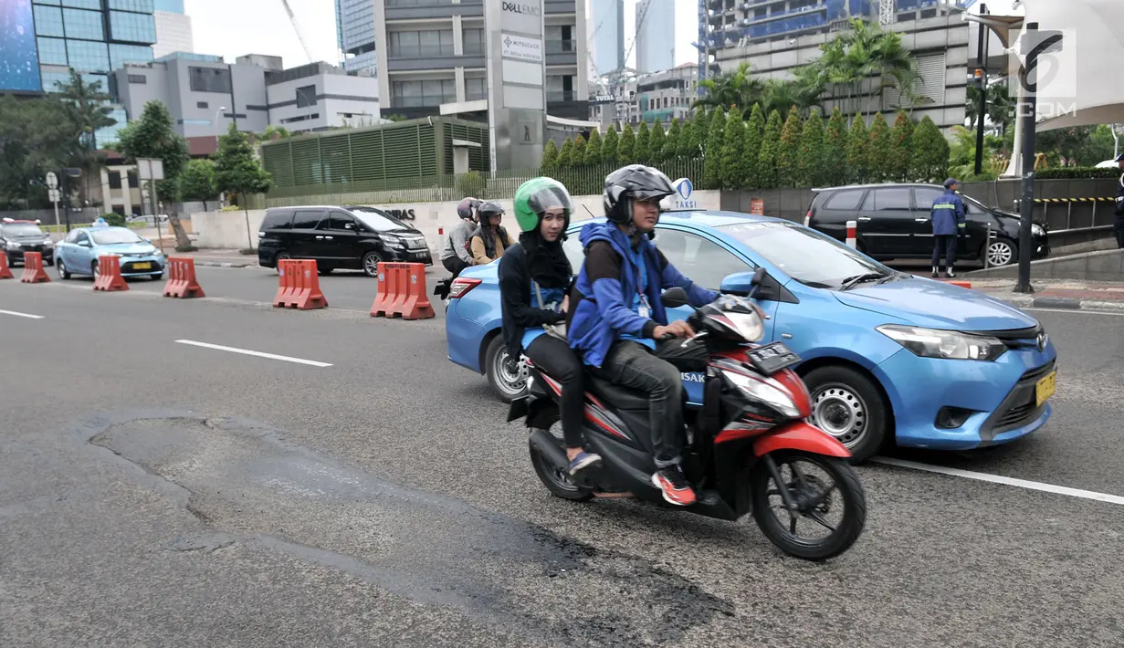 Kendaraan melintas di dekat jalan berlubang di Jalan Jenderal Sudirman, Jakarta, Senin (11/3). Jalanan di pusat kota tersebut berlubang dapat membahayakan keselamatan pengendara yang melintas. (merdeka.com/Iqbal S. Nugroho)