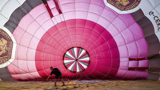 Seorang pilot memeriksa balon udara selama festival tahunan balon udara panas Bristol di Bristol, Inggris (8/8/2019). Festival balon udara ini diadakan selama empat hari dari 8-11 Agustus 2019. (Ben Birchall/PA via AP)