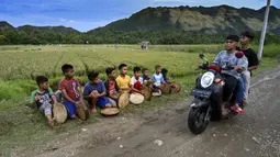 Sejumlah anak laki-laki memainkan rebana tradisional saat mengambil bagian dalam tari Rapa'i Geleng di sepanjang sawah di desa ekowisata Nusa, Lhoknga, Provinsi Aceh, 26 September 2021. Tarian ini mengekspresikan dinamisasi masyarakat dalam syair, kostum, dan gerak. (CHAIDEER MAHYUDDIN/AFP)