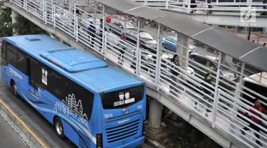 Calon penumpang melintasi jembatan saat hendak menggunakan bus Transjakarta di halte Tosari, Jakarta, Kamis (26/7). Gubernur DKI Jakarta Anies Baswedan mengklaim jumlah penumpang Transjakarta meningkat hingga 10 persen. (Merdeka.com/Iqbal S. Nugroho)