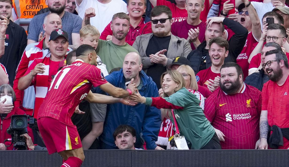 Pemain Liverpool, Mohamed Salah mengambil gawai dari salah satu suporter timnya untuk berswafoto setelah mencetak gol ke gawang Tottenham Hotspur dalam laga lanjutan Liga Inggris 2024/2025 di Anfiled, Liverpool, Inggris, Minggu (27/04/2025) waktu setempat. (AP Photo/Jon Super)
