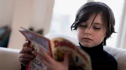 Mahasiswa Belgia Laurent Simons, 9 tahun membaca buku di rumahnya di Amsterdam (21/11/2019). Usai meraih gelar sarjana, Laurent rencananya akan studi ke jenjang yang lebih tinggi. Laurent akan belajar untuk meraih gelar PhD sekaligus mempelajari ilmu kedokteran. (AFP Photo/Kenzo Tribouillard)