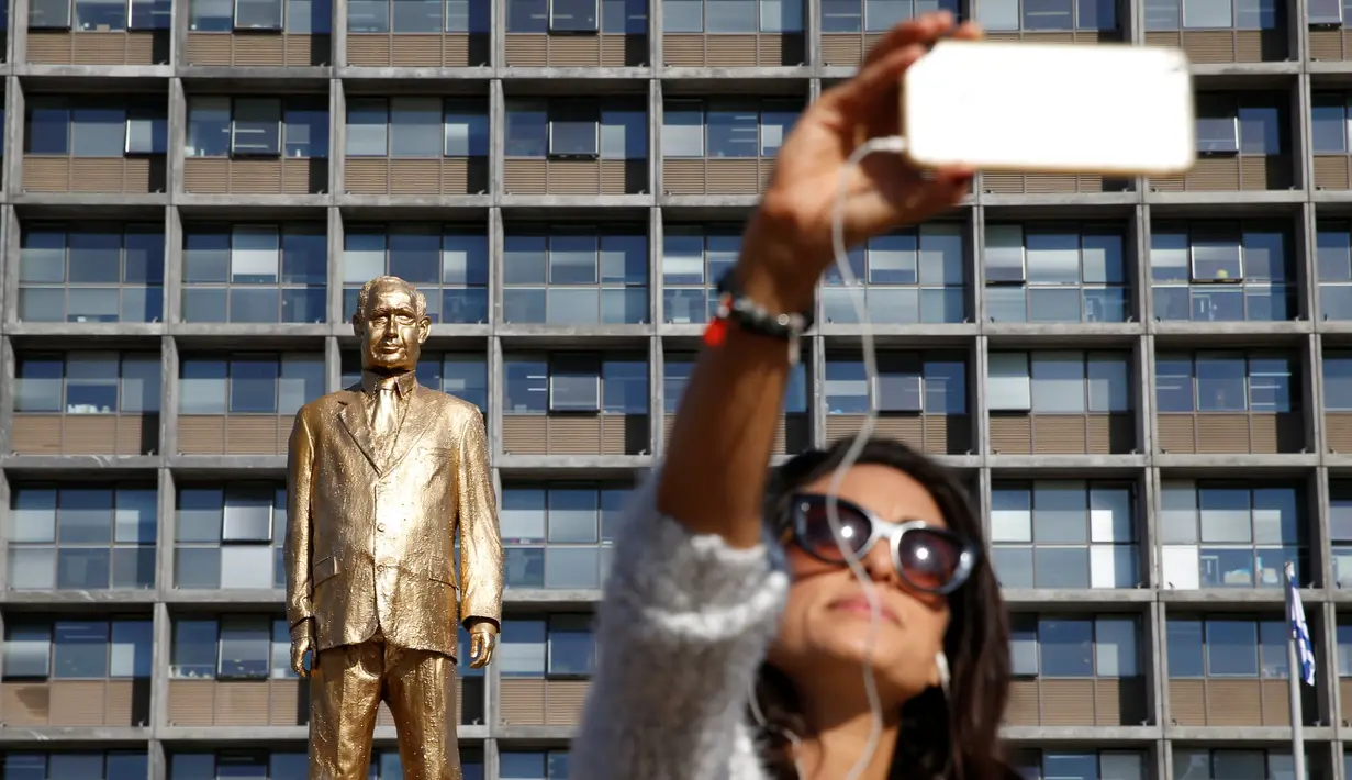 Warga berselfie di depan patung emas PM Israel Benjamin Netanyahu di Rabin Square, Tel Aviv, Selasa (6/12). (REUTERS / Baz Ratner)