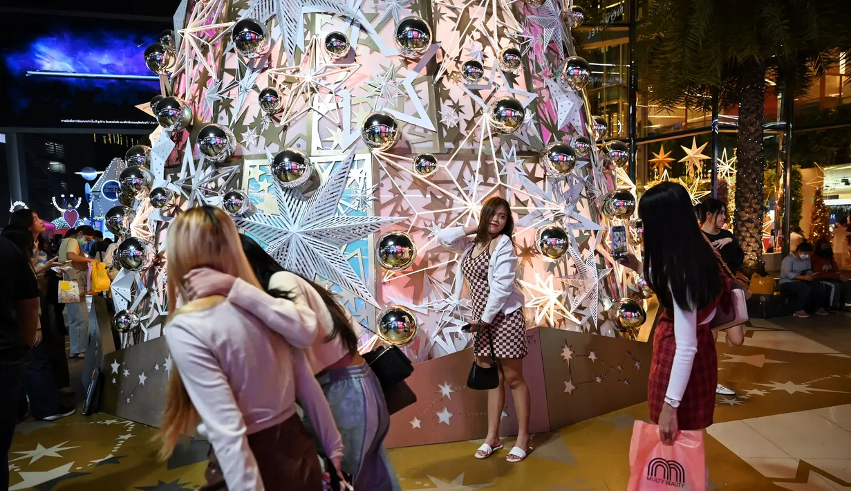 Orang-orang berfoto dengan dekorasi Natal di depan pusat perbelanjaan di Bangkok (21/12/2021). Menyambut Natal, dekorasi unik dan lucu ditampilkan di depan pusat perbelanjaan di Bangkok. (AFP/Lillian Suwanrumpha)