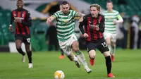 Gelandang AC Milan, Jens Petter Hauge, Berebut bola dengan bek Celtic, Jack Hendry, pada laga Grup H Liga Europa 2020/2021 di Celtic Park Stadion, Jumat (23/10/2020). AC Milan menang 3-1 atas Celtic. (AFP/Russell Cheyne/pool)