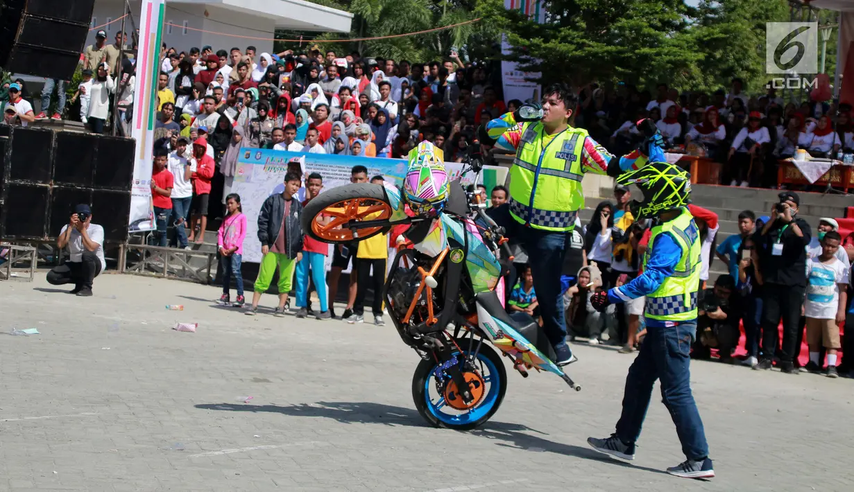 Aksi freestyle motor saat menghibur warga selama kegiatan Millenial Road Safety Festival Gorontalo, Minggu (10/2). Kegiatan ini juga diisi dengan lomba savety riding untuk umum. (Liputan6.com/Rahmad Arfandi Ibrahim)