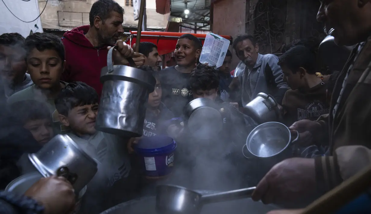 Warga yang ingin mendapatkan sup gratis ini membawa wadah sendiri dari rumahnya.  (AP Photo/Fatima Shbair)