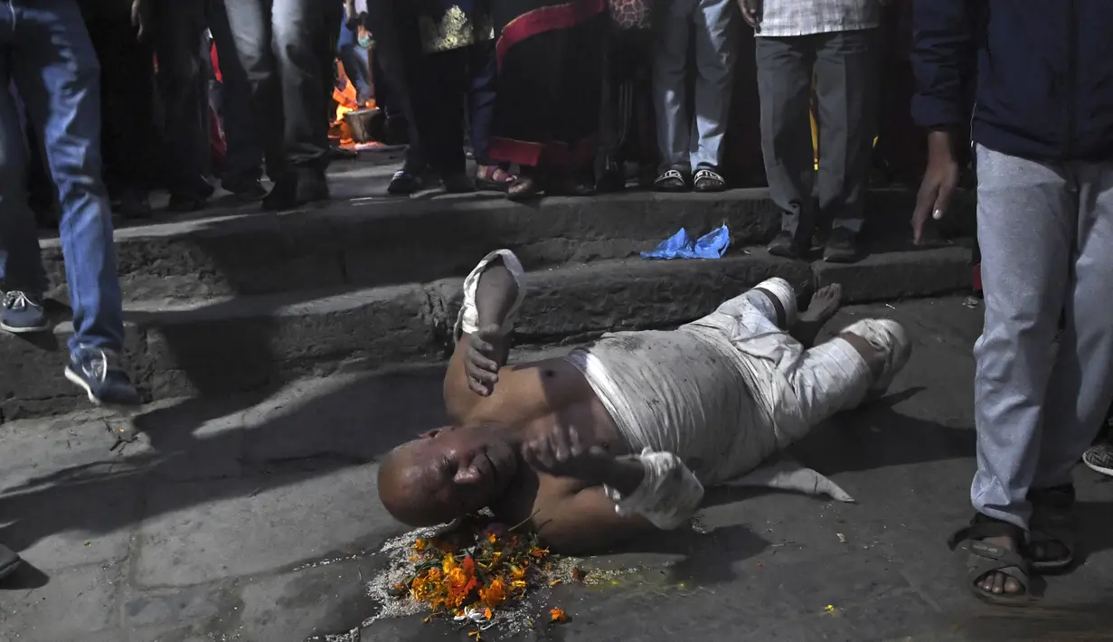 Seorang umat Hindu berdoa dengan berguling-guling di tanah selama perayaan pada hari kesepuluh festival Dashain di sebuah kuil di Bhaktapur di pinggiran Kathmandu, Nepal (15/10/2021). (AFP/Prakash Mathema)