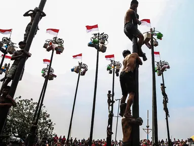 Peserta mengikuti perlombaan panjat pinang di pantai Ancol, Jakarta, Sabtu (17/8/2024). (Liputan6.com/Angga Yuniar)