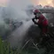 Petugas pemadam kebakaran membawa peralatan mereka saat berupaya memadamkan kebakaran lahan gambut di Palembang, Sumatra Selatan, Indonesia, Selasa, 11 Agustus 2026. (Foto AP/Muhammad Hatta)