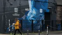 Seorang perempuan berjalan melewati mural perawat yang baru-baru ini dibuat di Manchester, Inggris, pada 5 November 2020. Inggris memasuki karantina wilayah (lockdown) selama sebulan mulai Kamis (5/11) untuk meredam merebaknya kembali penularan virus corona. (Xinhua/Jon Super)