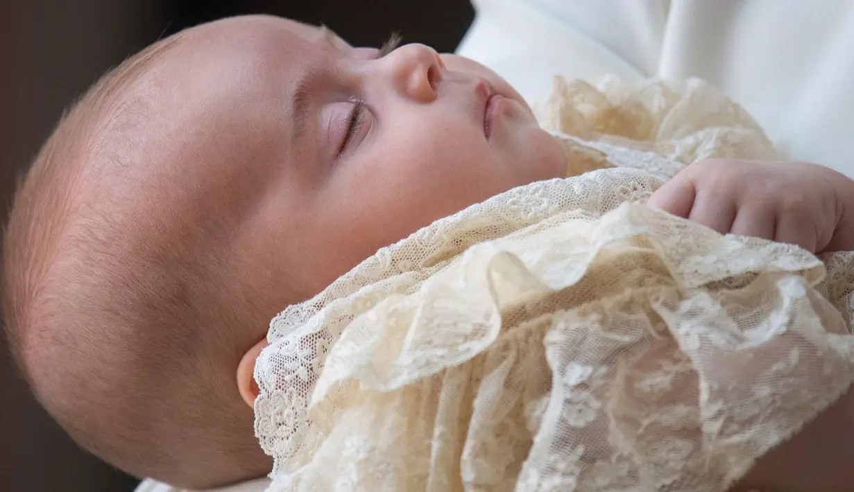 Kate Middleton menggendong Pangeran Louis pada acara pembaptisan di Chapel Royal, St. James Palace, London, Senin (9/7). Louis memakai gaun satin dengan lace, replika dari gaun untuk anak pertama Ratu Victoria di tahun 1841. (Dominic Lipinski/Pool via AP)