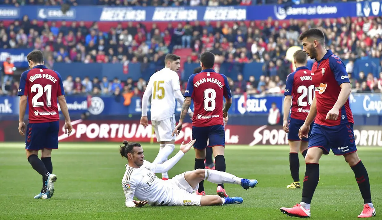 Penyerang Real Madrid, Gareth Bale, terjatuh saat berebut bola dengan pemain Osasuna pada laga La Liga di Stadion El Sadar, Minggu (9/2/2020). Real Madrid menang 4-1 atas Osasuna. (AP/Alvaro Barrientos)