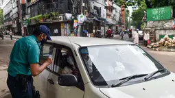 Seorang polisi memeriksa pengendara di sebuah pos pemeriksaan di Dhaka, Bangladesh, Kamis (1/7/2021). Tentara dan polisi diperintahkan untuk mencegah orang-orang keluar rumah, kecuali untuk keadaan darurat atau membeli kebutuhan pokok. (AFP/Munir Uz zaman)
