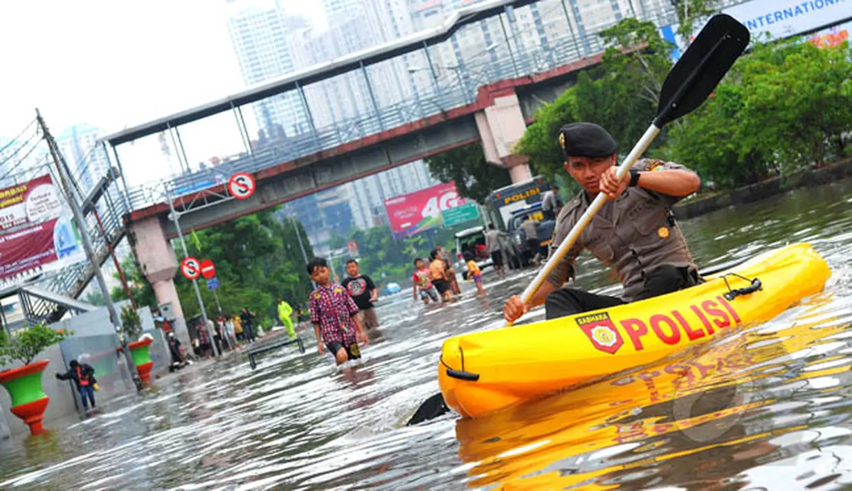 Seorang petugas polisi menggunakan perahu karet untuk melewati banjir yang menggenangi kawasan Grogol, Jakarta Barat, Rabu (11/2/2015). (Liputan6.com/Faisal R Syam)
