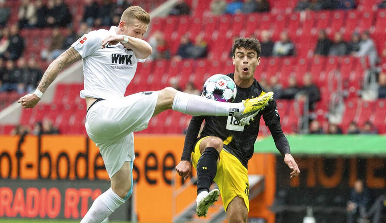 Pemain Borussia Dortmund, Giovanni Reyna, berebut bola dengan pemain Augsburg, Andre Hahn, pada laga Bundesliga, Minggu (27/9/2020). Augsburg menang dengan skor 2-0. (Matthias Balk/dpa via AP)