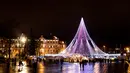 Pengunjung berjalan di sekitar pohon Natal raksasa yang berdiri di Alun-Alun Katedral di Vilnius, Lithuania, 1 Desember 2017. Cahayanya yang berkilauan membuat pohon Natal ini begitu mencolok di antara bangunan lain disekitar. (AP Photo/Mindaugas Kulbis)