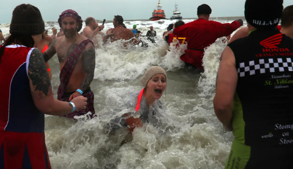 Warga Belgia menceburkan diri ke perairan Laut Utara untuk merayakan akhir pekan perrtama 2019 di Ostend, Sabtu (5/1). Tak sekadar bermain air, sebagian warga juga beraksi dengan kostum berwarna-warni. (AP/Francisco Seco)