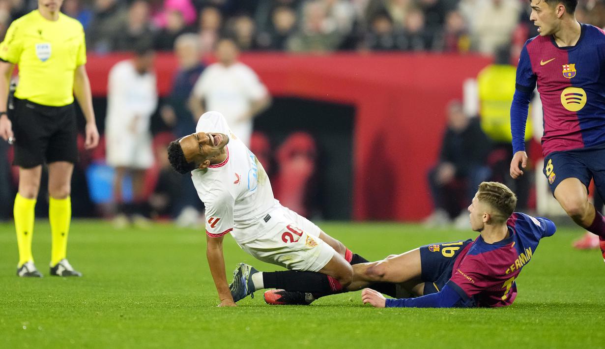 Pemain Barcelona, Fermin Lopez melakukan tekel keras kepada pemain Sevilla, Djibril Sow dalam laga lanjutan Liga Spanyol 2024/2025 di Ramon Sanchez Pizjuan Stadium, Sevilla, Spanyol, Senin (10/02/2025) dini hari WIB. (AP Photo/Jose Breton)