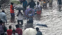 Orang-orang mengarungi jalan yang banjir setelah hujan lebat di Chennai, India (8/11/2021). Departemen Meteorologi India (IMD) memperkirakan lebih banyak curah hujan dalam beberapa hari mendatang. (AFP/Arun Sankar)