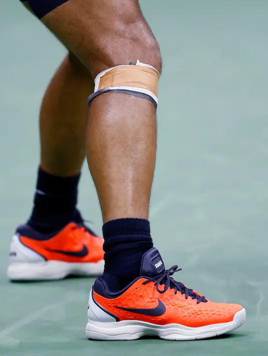 Petenis Spanyol, Rafael Nadal menggunakan bebat pada lututnya saat melawan Juan Martin del Potro dari Argentina pada laga semifinal AS Terbuka 2018, Jumat (7/9). Nadal memutuskan untuk mengundurkan diri setelah melakoni dua set. (AP/Adam Hunger)