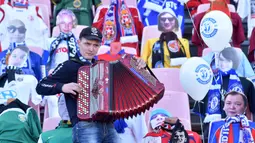 Seorang pria bermain akordion di depan maneken yang menggantikan penonton saat Liga Belarusia antara FC Dynamo-Brest dan FC Isloch di Brest, Minggu (12/4/2020). Kompetisi teratas Liga Belarusia ini menjadi satu-satunya liga di Eropa yang masih berjalan di tengah pandemi corona. (Sergei GAPON/AFP)