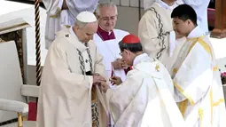 Kardinal Filipina Luis Antonio Gokim Tagle memasang Cincin Nelayan di jari Paus Leo XIV dalam sebuah misa awal masa kepausannya, di alun-alun Santo Petrus, Vatikan, pada Minggu 18 Mei 2025. (Filippo MONTEFORTE/AFP)