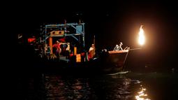 Nelayan Taiwan saat mencari ikan menggunakan api sebagai umpan di perairan New Taipei City, Taiwan, (19/6). Kini Metode tradisional ini hanya digunakan segelintir nelayan dan tersisa tiga kapal saja setiap malam. (REUTERS/Tyrone Siu)