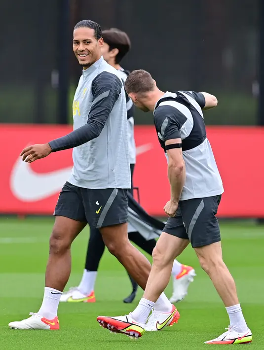 Bek Liverpool, Virgil van Dijk (kiri) tersenyum selama sesi latihan di pusat pelatihan Axa di Kirkby, Liverpool, Inggris (14/9/2021). Liverpool akan bertanding melawan wakil Italia, AC Milan pada Grup B Liga Champions di Anfield. (AFP/Paul Ellis)