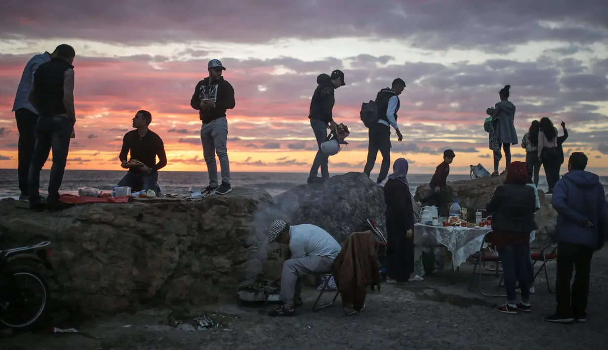 Pengunjung pantai menikmati keindahan matahari terbenam jelang berbuka puasa di pantai Rabat, Maroko (9/6). Selama Ramadan, banyak warga Maroko berkunjung ke pantai menikmati angin Atlantik dan menikmati pemandangan laut. (AP Photo/Mosa'ab Elshamy)