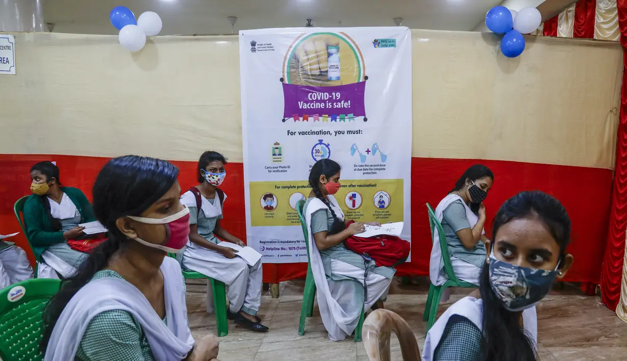 Gadis-gadis sekolah menunggu untuk disuntik vaksin COVID-19 di sebuah sekolah di Kolkata, Senin (3/1/2022). India mulai memvaksinasi remaja usia 15-18 tahun saat banyak negara bagian memberlakukan pembatasan ketat untuk menahan lonjakan infeksi yang dipicu oleh varian omicron. (AP Photo/Bikas Das)