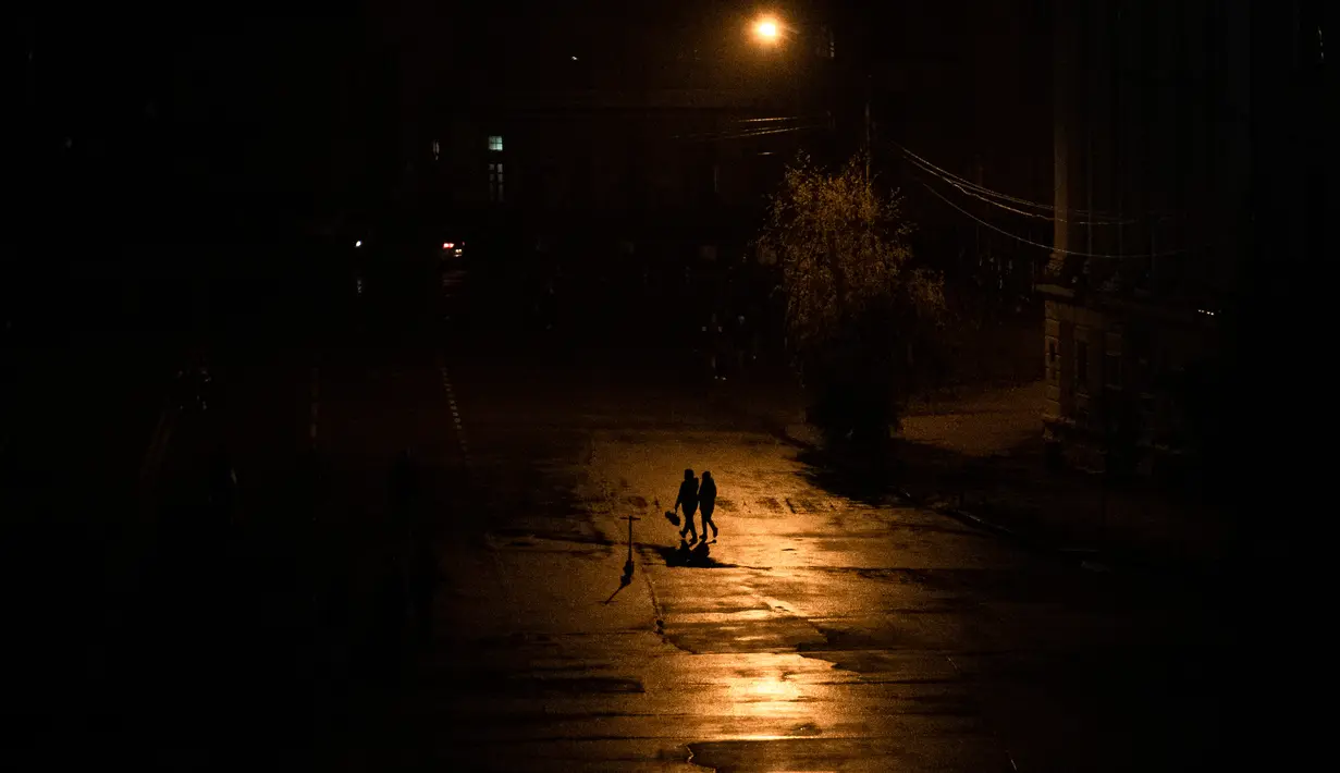 Orang-orang berjalan di seberang jalan saat pemadaman listrik di Kiev, Ukraina, 6 November 2022. Pemadaman listrik bergilir di Kiev dilakukan untuk menghindari kelebihan beban dan memungkinkan perbaikan. (AP Photo/Andrew Kravchenko)