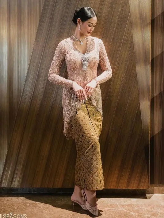 Ia memadukan kebaya brokat berpotongan asimetris tersebut dengan kain batik warna coklat. [@allseasonsphoto].