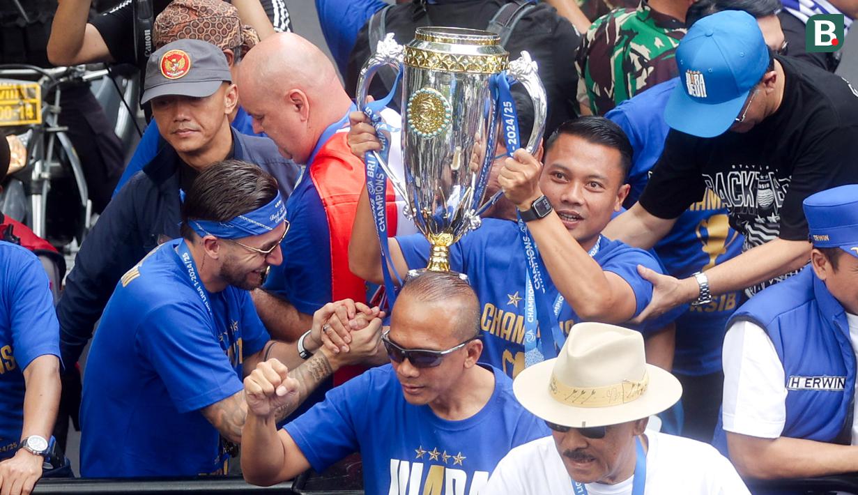 Pemain Persib Bandung, Dedi Kusnandar, mengangkat trofi saat pawai juara di Bandung, Minggu (25/5/2025). (Bola.com/M Iqbal Ichsan)