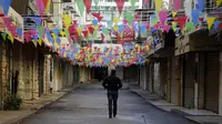 Seorang pria Palestina berjalan melewati toko-toko yang tutup di kota Nablus, Tepi Barat, (7/12). Usai Presiden AS, Donald Trump mengumumkan Yerusalem sebagai ibu kota Israel suasana sepi terlihat di kawasan tersebut. (AFP Photo/Jaafar Ashtiyeh)
