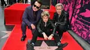 Personel grup band punk rock Green Day, Billie Joe Armstrong (tengah), Mike Dirnt (kanan), dan Tre Cool berpose dengan bintang mereka yang baru saja diresmikan di Hollywood Walk of Fame dalam sebuah upacara di Hollywood, California, Amerika Serikat pada 1 Mei 2025. (Frederic J. Brown/AFP)