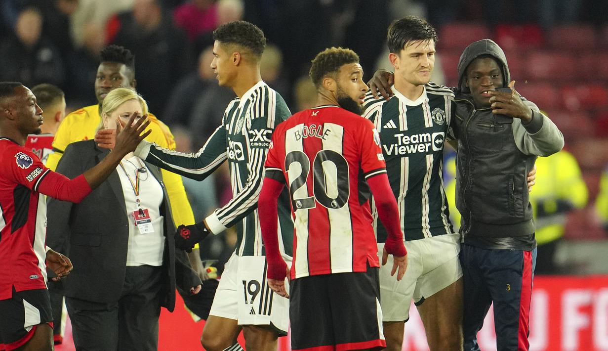 Seorang fans melakukan selfie bareng bek Manchester United, Harry Maguire setelah berakhirnya laga pekan ke-9 Liga Inggris 2023/2024 antara Sfheffield United menghadapi Manchester United di Bramall Lane, Sheffield, Minggu (22/10/2023) dini hari WIB. (AP Photo/Jon Super)