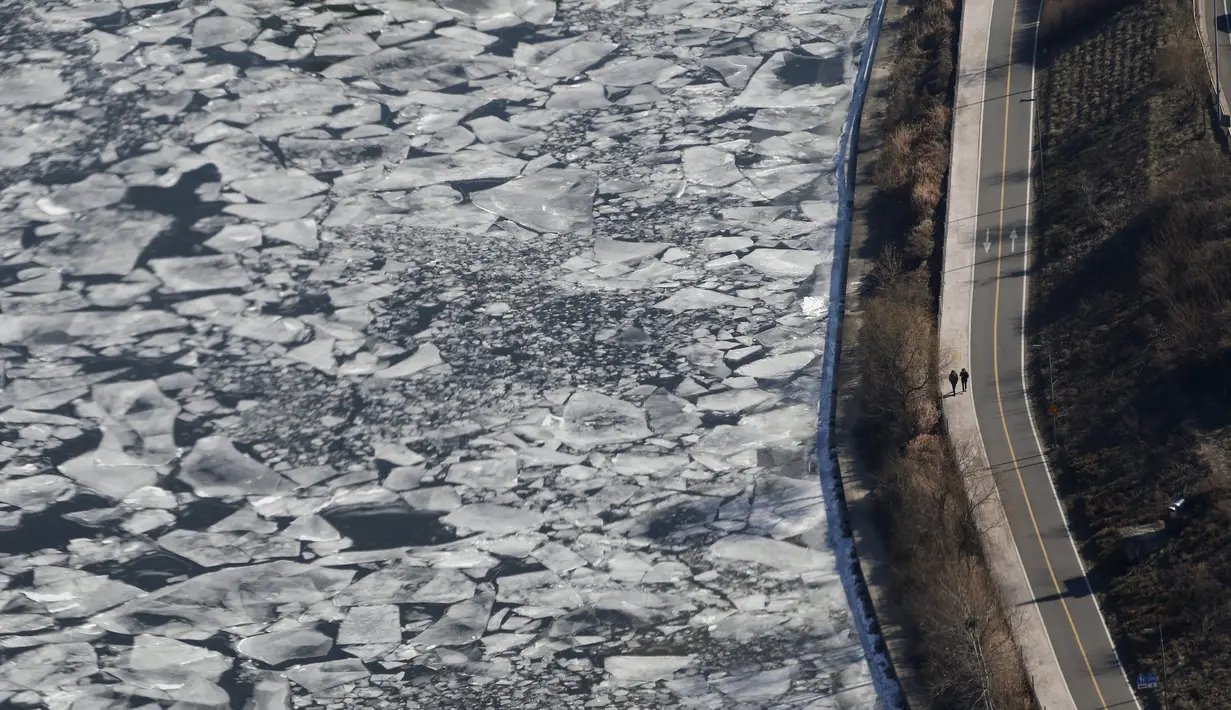  Warga berjalan di dekat Sungai Han yang membeku di Korea Selatan, Senin (25/1). Sungai Han yang terletak dekat dengan pusat jantung kota Seoul, membeku akibat suhu di Korea yang kini mencapai minus dol derajat Celsius. (REUTERS/Kim Hong - Ji)