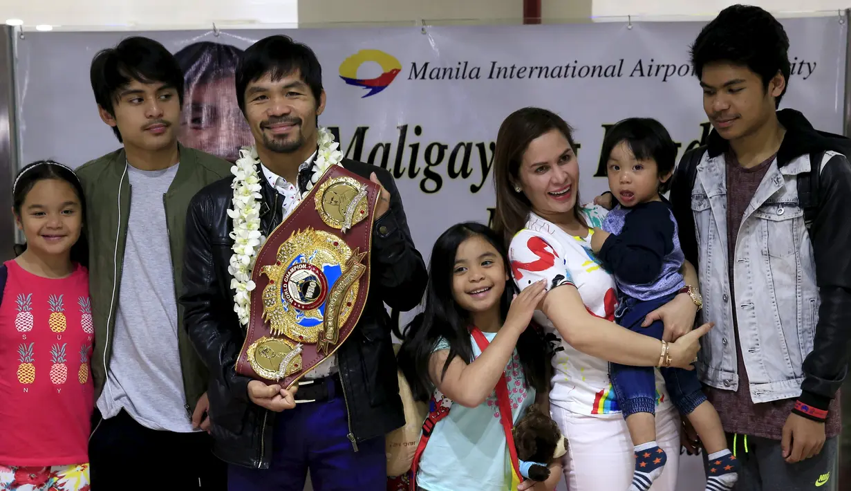 Petinju asal Filipina, Manny Pacquiao foto bersama keluarganya dan menunjukkan sabuk WBO kepada awak media usai mengalahkan Timothy Bradley setibanya di Bandara Internasional Ninoy Aquino, Manila (14/4). (REUTERS/Romeo Ranoco)