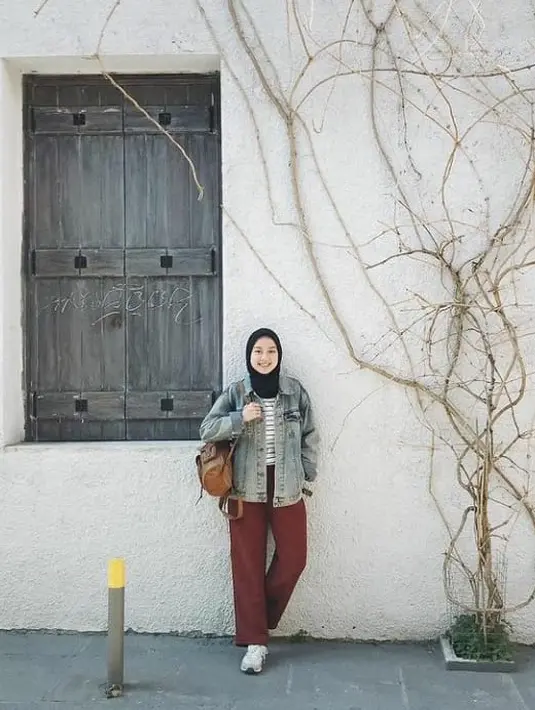 Saat traveling, Gita memadukan sweatshirt stripe dan jaket jeans dengan celana kulot warna brick. Stylish effortless!. (Instagram/gitasav).