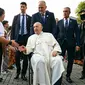 Sebelum masuk ke dalam, Paus Fransiskus berkeliling menemui sejumlah anak yang berdiri menjadi pagar betis menyambut kedatangannya. (Tiziana FABI/AFP)