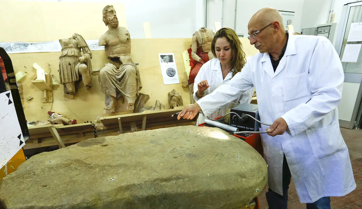 Stefano Sarri dan asistennya saat melakukan restorasi terhadap prasasti Etruscan di Florence , Italia , 20 April 2016.Prasasti itu ditemukan tertanam dalam pondasi kuil yang terkubur selama lebih dari 2.500 tahun. (REUTERS / Remo Casilli)