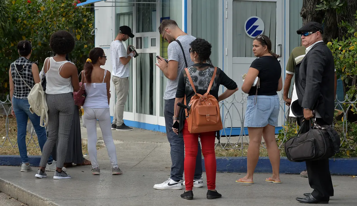 Orang-orang menggunakan ponsel mereka untuk terhubung ke internet melalui WiFi di sebuah taman di Havana, Rabu (5/12). Kuba merupakan salah satu negara terakhir di dunia yang masih belum menerapkan internet mobil. (YAMIL LAGE/AFP)