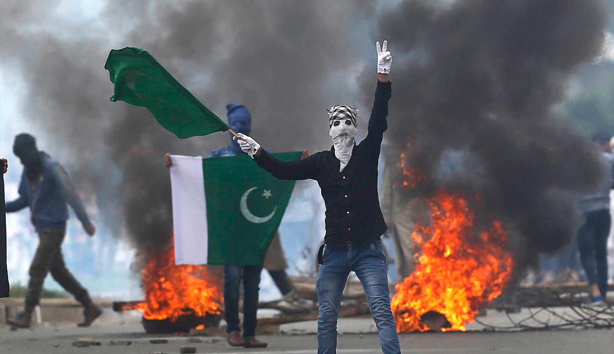 Seorang demonstran mengibarkan bendera Pakistan dan meneriakkan slogan-slogan anti-India saat menggelar aksinya usai melakukan salat Idul Fitri di Srinagar, India (26/6). (AP Photo / Mukhtar Khan)