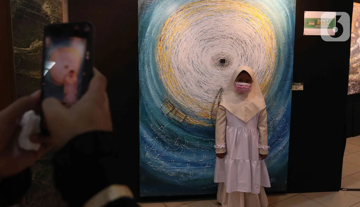 Seorang anak berpose saat Pameran Kaligrafi Kontemporer Internasional di Masjid Raya Jakarta Islamic Center, Jakarta, Senin (18/4/2022). Pameran digelar dalam rangkaian peringatan Nuzulul Quran menghadirkan lebih dari 100 karya seniman kaligrafi dari 26 negara. (Liputan6.com/Herman Zakharia)