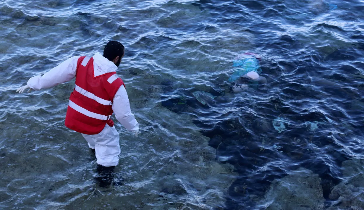 Seorang petugas menemukan mayat yang terapung di pantai di Kota Pesisir Tajoura, Libya, Minggu (4/12). Diduga orang yang tenggelam itu akan meninggalkan Libya karena berharap dapat menjadi imigran di negara lain. (REUTERS / Hani Amara)