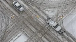 Kendaraan melewati persimpangan Rose Street dan West Michigan Avenue selama badai salju di pusat kota Kalamazoo, Michigan, Rabu (2/2/2022). Badai salju membuat maskapai membatalkan ratusan penerbangan. (Joel Bissell/Kalamazoo Gazette via AP)