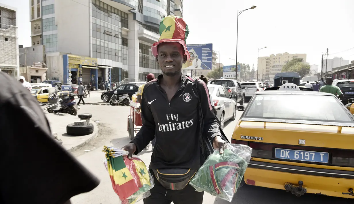 Seorang pedagang kaki lima membawa dagangannya di Dakar (4/2/2022). Senegal akan bertanding melawan Mesir pada babak final Piala Afrika 2021 di Paul Biya stadium, Senin (7/2/2022) dini hari WIB besok. (AFP/Seyllou)