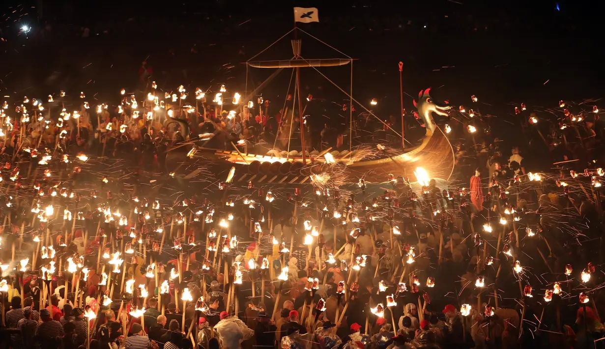 Anggota Jarl Squad mengelilingi replika kapal perang Viking sambil membawa obor selama festival Up Helly Aa Viking di Lerwick, Kepulauan Shetland, Skotlandia (31/1). Festival ini secara resmi digelar pertama kali pada tahun 1880. (Jane Barlow/PA via AP)