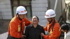 Petugas penyelamat membantu seorang wanita yang menangis di zona gempa di Longtoushan, provinsi Yunan, Tiongkok, (6/8/2014). (REUTERS/Stringer)